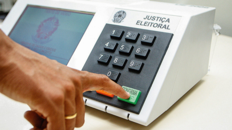 Quanto é a multa por não votar nas eleições brasileiras 26 cidadaos votando em uma urna eleitoral