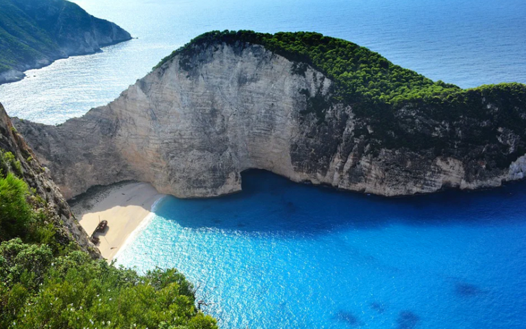 praia com aguas cristalinas e montanhas ao fundo