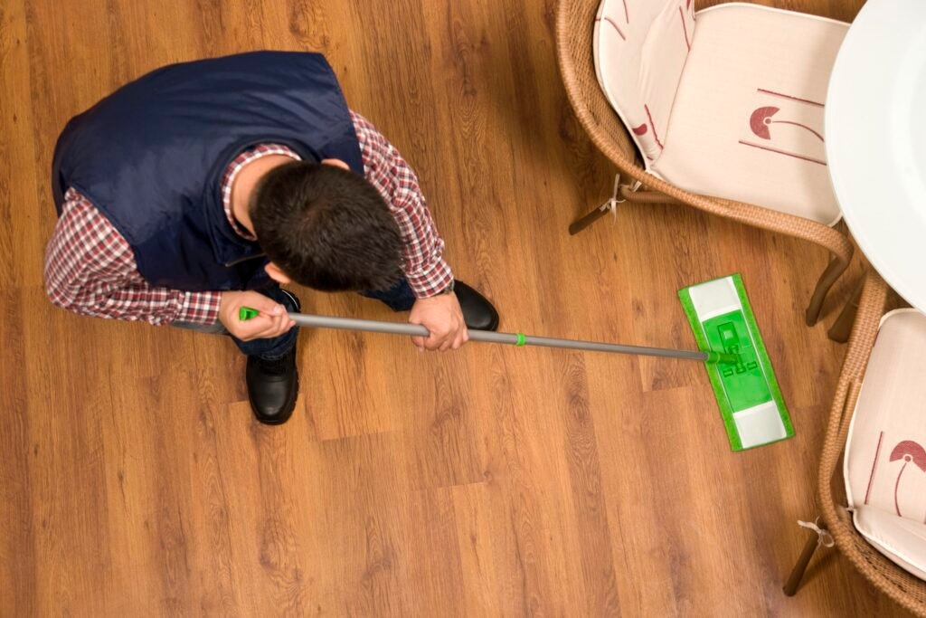 vassoura e pano em piso laminado brilhante